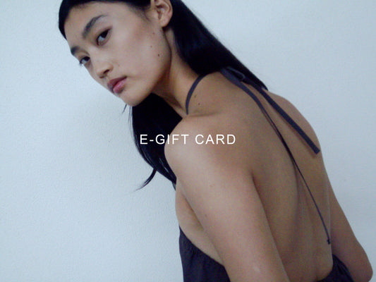 A person with long dark hair in a backless halter dress looks over their shoulder at a light background. Centered text reads e-gift card, inviting you to redeem e-gift cards in Australian Dollars.